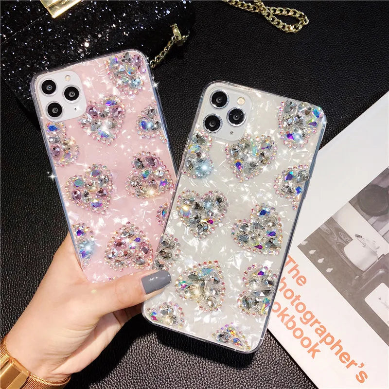 Two marble phone cases, one pink and one white, adorned with glitter rhinestone hearts.