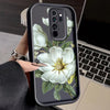 A black phone case with a white magnolia flower design is held in a hand.