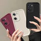 Three matte silicone phone cases in black, white, and wine red are held by hands.