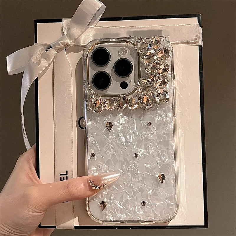 A clear phone case with a white marble pattern and silver diamonds, held by a hand.