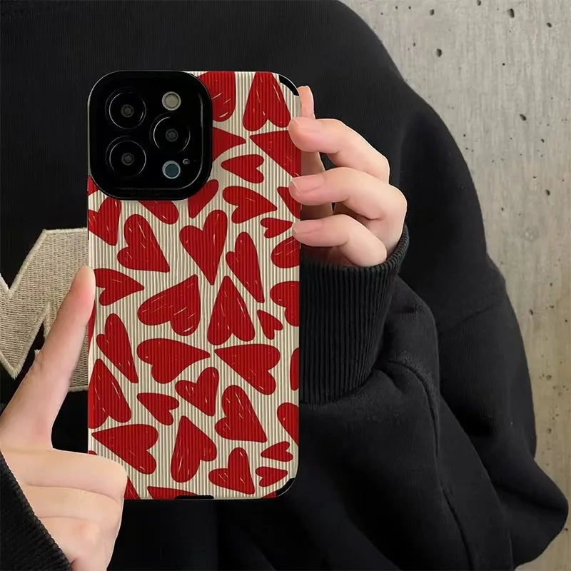 A person holds an iPhone with a red heart pattern case.