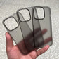 Three translucent matte black phone cases are held in a hand.