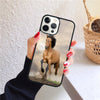 A hand holds an iPhone with a case featuring a running brown horse on a dusty path.